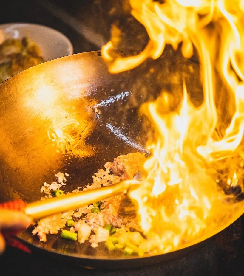 Wok cooking over high heat for zi char style catering in Singapore